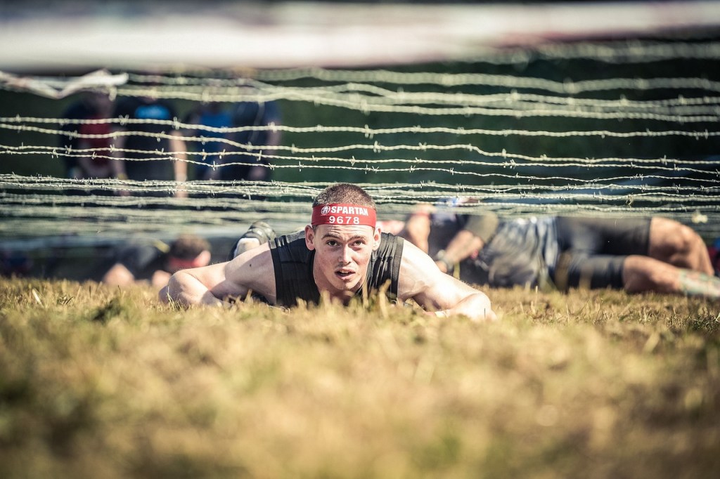 man climbing under barbed wire
